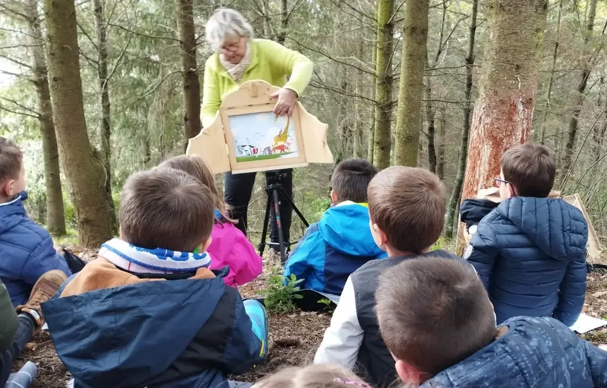 Michèle raconte une histoire kamishibaï en forêt à une classe de maternelle